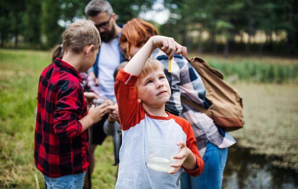 Group of school children with teacher on field trip in nature, learning science