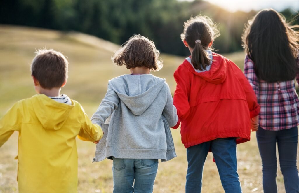 Rear view of group of school children walking on field trip in nature